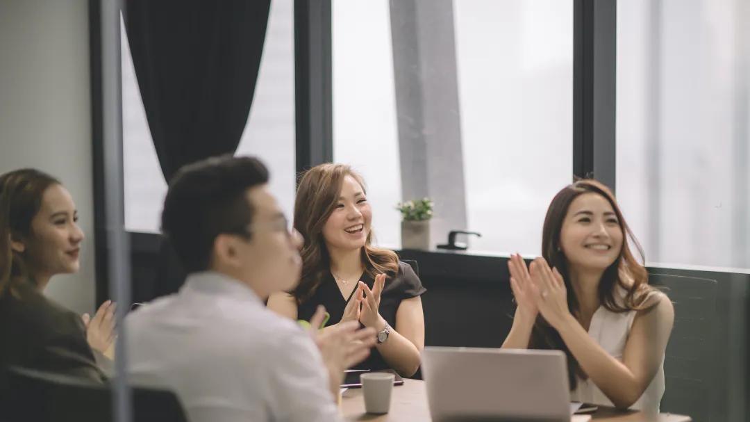 HOIIY Singapore corporate culture: A diverse group of people clapping in our modern office, welcoming new talent to the 8L Glass Air Fryer project.